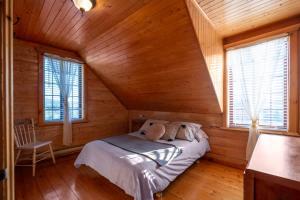 a bedroom with a bed in a wooden cabin at Rustic Chalet Hideaway - Hot Tub & Trail Access in Saint-Léonard-de-Portneuf