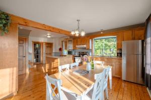 a kitchen with a wooden table and a refrigerator at Rustic Chalet Hideaway - Hot Tub & Trail Access in Saint-Léonard-de-Portneuf +45 photos