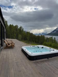a hot tub on a deck with a view of a lake at LyNora - A private fjord retreat in Indre Ravelseidet