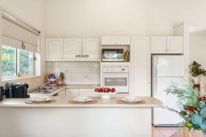 a kitchen with white cabinets and a counter with fruit on it at Harbour Creek in Ulladulla