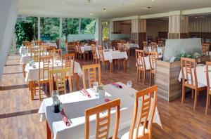 a restaurant with white tables and wooden chairs at Holiday Park Orava - Hotel Orava in Dolný Kubín