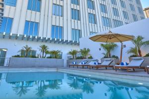 a pool with chairs and an umbrella next to a building at City Express Plus by Marriott Mexicali in Mexicali