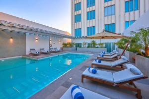 a pool at a hotel with lounge chairs and an umbrella at City Express Plus by Marriott Mexicali in Mexicali