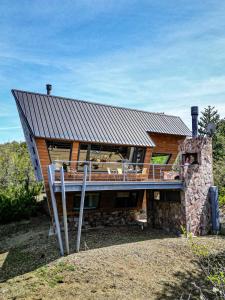 a log home with a large deck and a roof at Estrellas de la Laguna in Villa Pehuenia