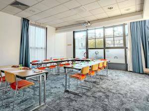 a conference room with tables and orange chairs at ibis Marne La Vallee Champs-sur-Marne in Champs-sur-Marne