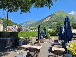 a patio with tables and umbrellas with mountains in the background at Hôtel Terminus in Luz-Saint-Sauveur