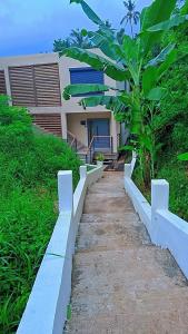 a pathway leading to a house with a palm tree at Résidence LE MÄYSA CORAIL in Sada