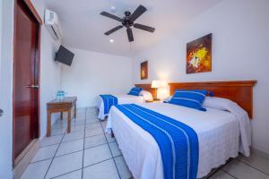 a bedroom with two beds and a ceiling fan at Hotel Meson de Mita in Punta Mita