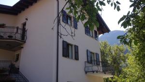 ein weißes Gebäude mit schwarzen Rollläden und Balkonen darauf in der Unterkunft B&B I Pioppi in Chiavenna