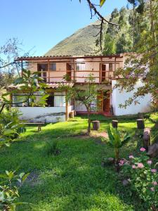 a house with a green yard in front of it at Casa Hospedaje Saywa in Lamay