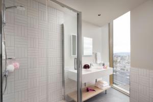 a bathroom with a shower and a sink and a mirror at Moxy Dublin Docklands in Dublin +35 photos