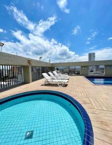 a swimming pool with a group of chairs next to a building at Flat São Vicente Praia Piscina Garagem in São Vicente