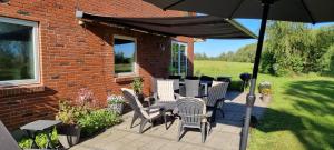 a patio with a table and chairs and an umbrella at Kastanjegaarden in Ansager