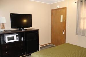 a bedroom with a television on a dresser with a bed at Colonial Inn in Dyersville