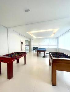 a large room with two tables and a pool table at Flat São Vicente Praia Piscina Garagem in São Vicente