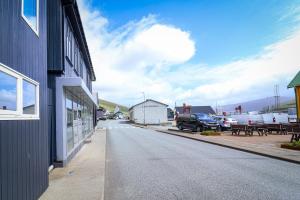 an empty street next to a building with cars parked at Spacious 3-Bedroom Apartment with Comfy Beds in Central Vágur, Island of Suðuroy in Vágur