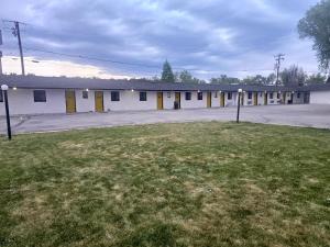 an empty building with yellow doors and a grass field at JET Motor Inn - Buffalo in Buffalo