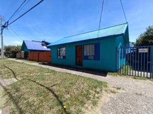 a blue and green house with a fence at Cabaña Aldea 31 in Coihaique