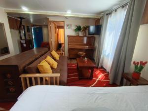 a room with a bed and a couch and a piano at Cabaña Aldea 31 in Coihaique