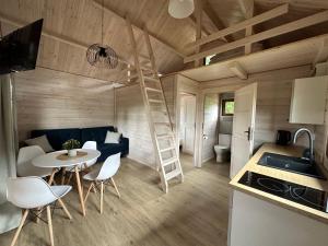 a kitchen and a living room with a staircase in a tiny house at Pięć Sosen in Wiele