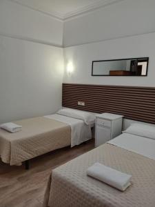 a hotel room with two beds and a mirror at Hostal Alcarayón Pilas in Pilas