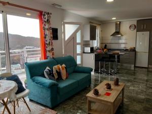 a living room with a blue couch and a kitchen at Alojamientos Harizan in Agaete