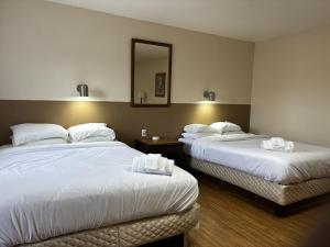 a hotel room with two beds and a mirror at JET Motor Inn - Buffalo in Buffalo