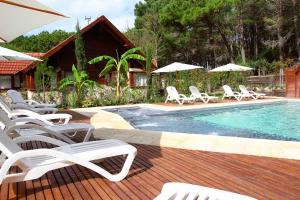 una piscina con sillas y sombrillas junto a una casa en Cabañas del Bosque en Balneario Mar Azul