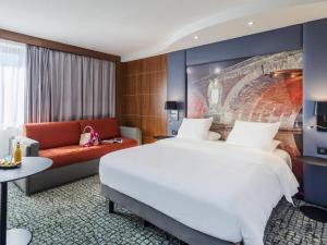 a hotel room with a large bed and a couch at Hotel Mercure Toulouse Centre Compans in Toulouse +182 photos
