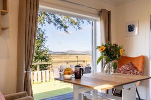 a table with a vase of flowers and a window at Green Law - Dog Friendly in Penicuik