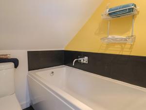 a bathroom with a bath tub and a yellow wall at Pottery Barn in Branscombe +33 photos