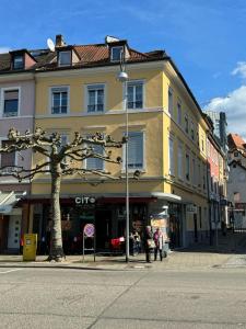 a yellow building on a street with people standing outside at Baden-Baden Zentrum Studio in Baden-Baden