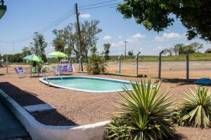 a small swimming pool with chairs and umbrellas in a park at Hotel Popular in Pântano Grande