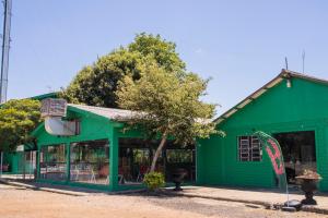 a green building with a tree in front of it at Hotel Popular in Pântano Grande