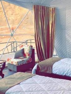 a bedroom with a bed and a chair and a window at Golden Camp- wadi rum in Wadi Rum