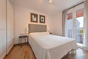 a white bedroom with a bed and a window at La Cepa Apartamentos in Alhama de Granada
