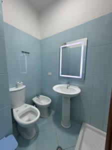 a bathroom with a toilet and a sink and a mirror at Alfas Beach Apartments in Shëngjin