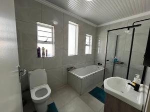 a bathroom with a tub and a toilet and a sink at Exquisite cottage in Doringkloof in Centurion