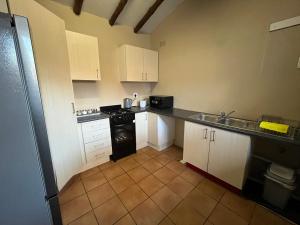 a kitchen with white cabinets and a black stove at Exquisite cottage in Doringkloof in Centurion +6 photos