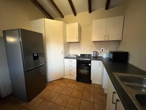 a kitchen with white cabinets and a black refrigerator at Exquisite cottage in Doringkloof in Centurion