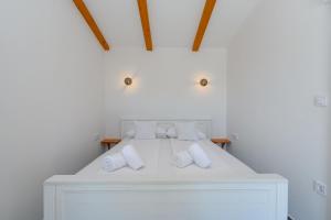 a white bed with white pillows on top of it at House Guesthouse Stipe in Lopar