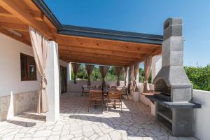 an outdoor patio with a fireplace and tables and chairs at House Guesthouse Stipe in Lopar