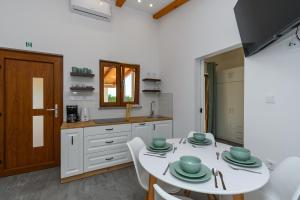 a kitchen with a white table and white cabinets and a table and chairs at House Guesthouse Stipe in Lopar
