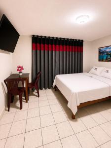 a bedroom with a bed and a table with a desk at Hospedaje W TAWA in Lima