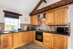 a kitchen with wooden cabinets and black counter tops at Carleton Mill Cottage in Carlisle +3 photos