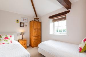 a bedroom with two beds and a window at Carleton Mill Cottage in Carlisle