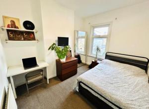 a bedroom with a bed and a desk with a laptop at Home Vibes in Hornchurch