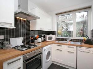a kitchen with white cabinets and a stove top oven at Home Vibes in Hornchurch