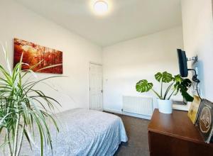 a bedroom with a bed and two potted plants at Home Vibes in Hornchurch