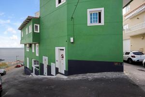 a green building with white windows and a parking lot at Casa Auxilia in Araya